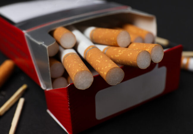 A pack of cigarettes with matches on a dark background